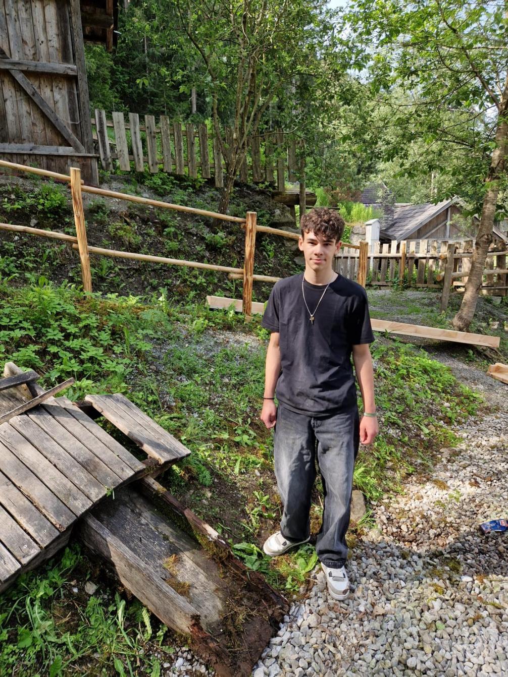 Schüler steht neben Holz