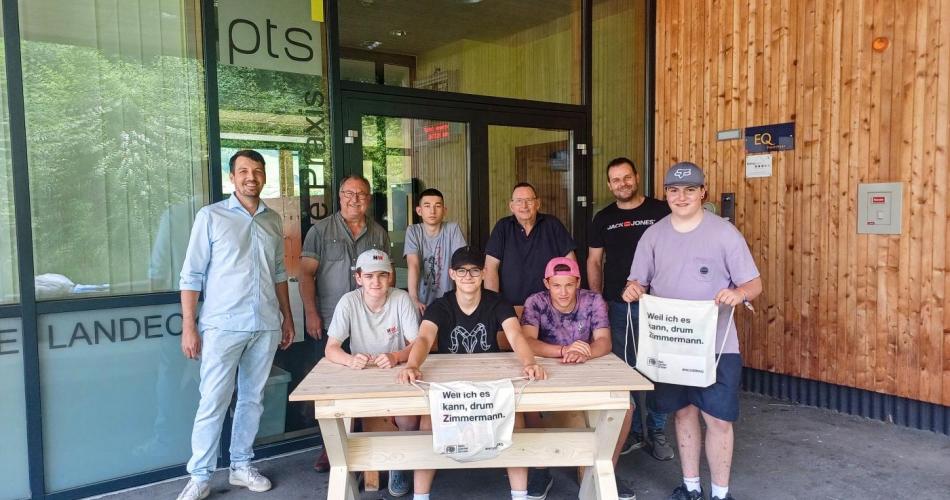 Zwei Mitarbeiter der Firma Orthner und die Schüler des Fachbereichs Bau-Holz